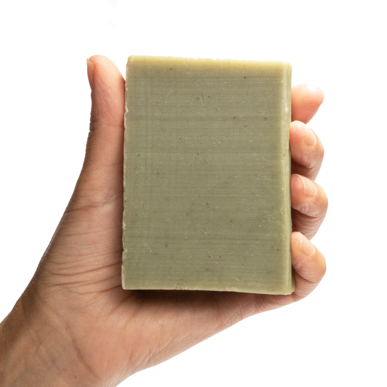 A naked bar of "Grove" cedar & pine essential oil and rhassoul clay organic bar soap from ground Soap in a hand.