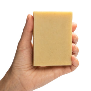 A naked bar of Plain Jane Unscented organic bar soap from ground Soap in a hand.